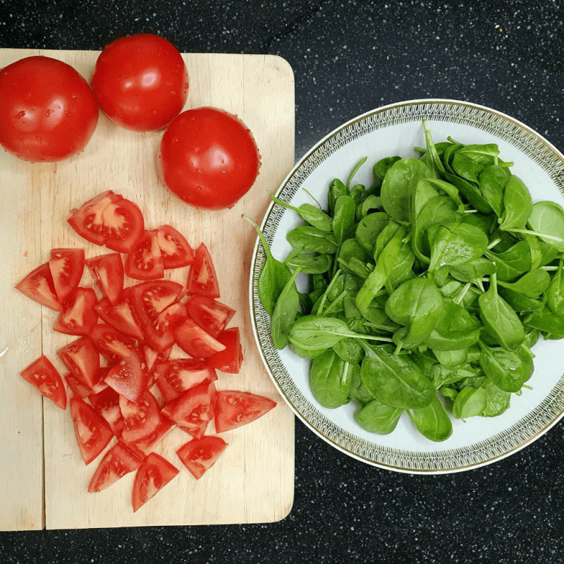 Foto von gewürfelten roten Tomaten und gewaschenem Spinat